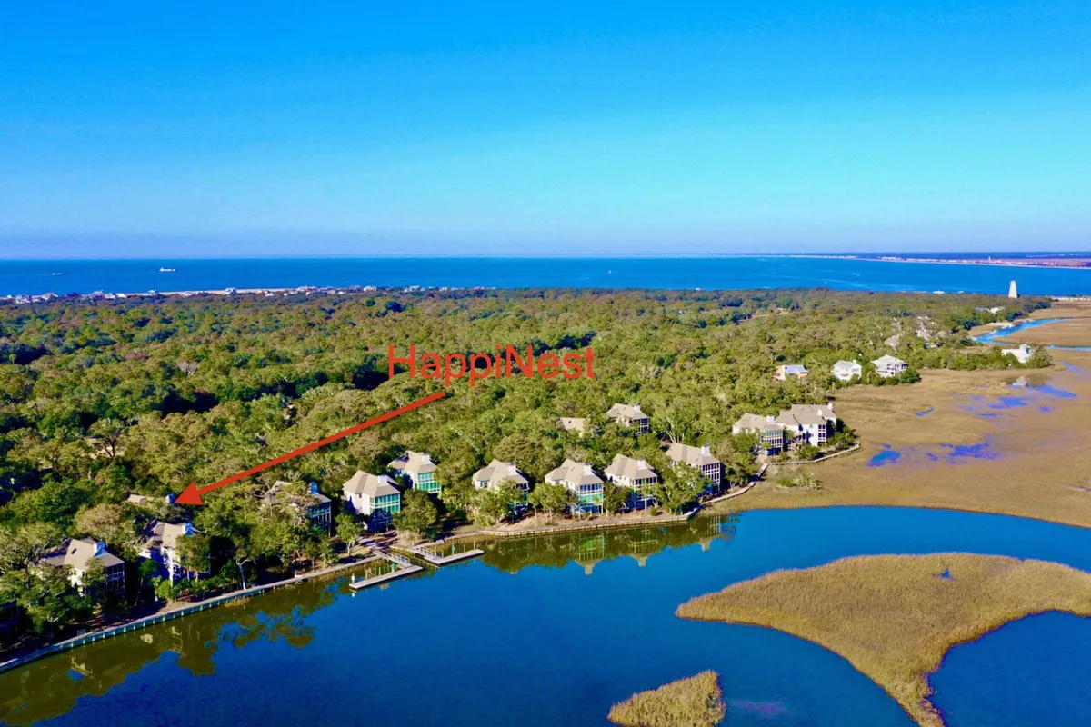 A broad view of the HappiNest property nestled among trees, with the waterway and marshland visible nearby. The scene conveys easy access to kayaking, nature walks, and opportunities to spot wildlife or unwind by the water, all from the comfort of the property’s surroundings.