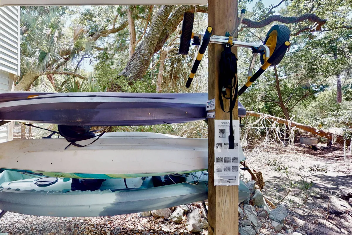 A collection of stacked kayaks with transport wheels is shown outdoors, ready for use. The vibrant colors of the kayaks stand out against the natural backdrop, suggesting excitement and active exploration on the water.